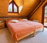 Attic room in a cabin with wooden paneling, a large window, and a bed.