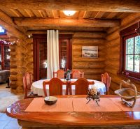 Interior of a cabin with wooden wall decor, a window with a view of the forest, dining table.