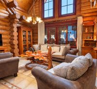 A stylish interior of a wooden cabin with comfortable seating and a TV.