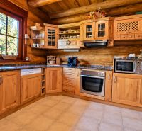 A kitchen in a cabin with wooden decor, equipped with appliances and rustic wooden cabinets.