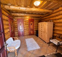 Interior of a cabin with wooden walls and tiles, a comfortable armchair and a cabinet.