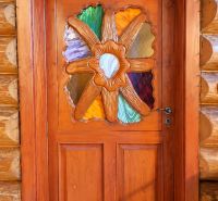 Wooden entrance door with a colorful glass motif in the cottage.
