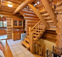 Wooden interior of a cabin with wooden staircase and rustic furniture.