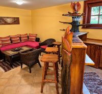 Interior of a cottage with rattan furniture, a bar, and colorful cushions on the sofa.