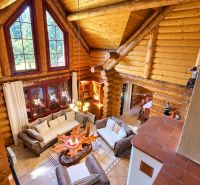 Interior of a cabin with a view of the living room, wooden walls, and large windows.