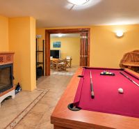 Interior of a cabin with a billiard table, fireplace, and wooden decor, suitable for recreation.