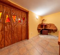 Interior of a cabin with wooden doors, a sofa set, and a pool table.