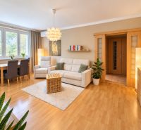 Living room with wood-patterned flooring in a 3-room apartment, light walls and furniture.