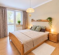 A bedroom in a 3-room apartment with a wooden decor floor and natural furniture.