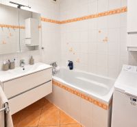 A bathroom with white tiles and orange accessories in a 3-room apartment.
