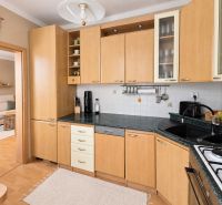 A kitchen in a 3-room apartment with a wooden decor floor and light furniture.