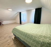 A bedroom in a family house with a wooden decor floor, a skylight, and a green blanket.