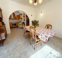 Dining area in a family house with wooden furniture and a floral tablecloth on the table.