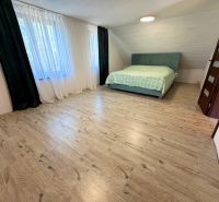 A bedroom with a double bed and a wooden decor floor in a family house.