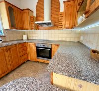 A kitchen in a family house with wooden cabinets, a sink, and a cooktop.
