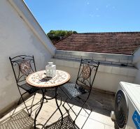 A balcony of a family house with a mosaic table against the backdrop of a sunny sky.