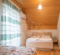 A bedroom in a cabin with two beds and curtains, floor with wooden decor.