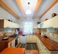 A kitchen in a cottage with wooden beams and a floor with a wooden decor.