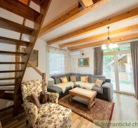 Living room in a cottage with wooden beams, a corner sofa, and a floral armchair.