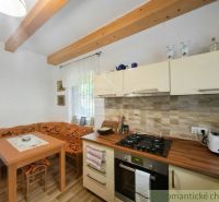 A kitchen in a cabin with wooden decor, a dining nook, and rustic details.