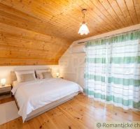 A bedroom in a cabin with a bed and a floor with a wooden decor, curtains with stripes.