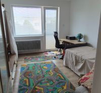 A room in a family house, with a bed, a desk, and a floor with a wooden decor.