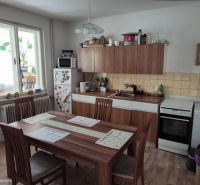 A kitchen in a family house with a dining table, white cabinets, and wooden decor.