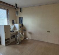Exercise bike and furniture in a room of a family house with a wooden decor floor.