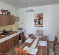 A kitchen in a family house with a dining table and kitchen unit, floor with wooden decor.