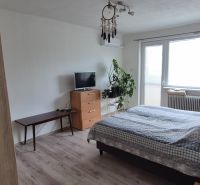 Bedroom in a family house with a TV, dresser, and wooden decor flooring.