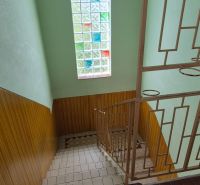 A staircase in a family house with a stained glass window and a tiled floor.