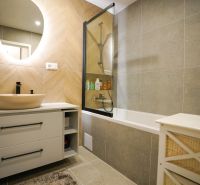 A bathroom with a bathtub and a mirror decorated with tiles in a 3-room apartment.
