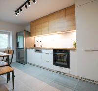 A kitchen in a 3-room apartment with a wooden decor and white cabinets.