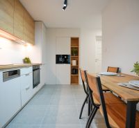 A kitchen in a 3-room apartment with wooden decor on the furniture and a dining table.