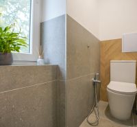 A bathroom in a 3-room apartment with a plant on the windowsill and walls with embossed tiles.
