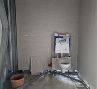 An unfinished bathroom in a family house with a mounted wall-hung toilet and preparation for tiling.