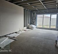 Interior of a family house under construction with a large window and building materials.