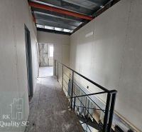 A hallway in a family house with wooden decor and metallic railing.