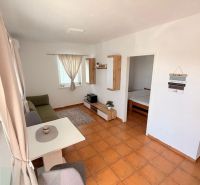 Living area of a studio apartment with a tiled floor and a dining table.