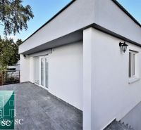 Terrace by the cottage in Senec at SUNNY LAKES SOUTH with a white facade and trees.