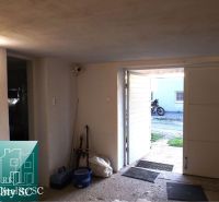 The garage of the cottage with open doors, from the view outside you can see a motorcycle.