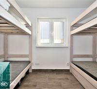 A cabin with two bunk beds, a wooden decor floor, a window in the middle.