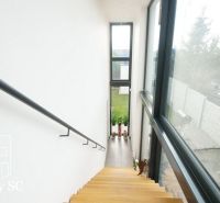 A staircase with large windows, overlooking the garden in a family house.