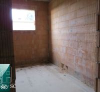 Unplastered brick walls in a room of a family house, with a window on the wall.