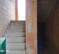 In the family house, concrete stairs and brick walls without plaster can be seen.