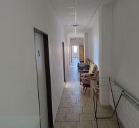 A corridor with a light floor, a ceiling with a soffit, chairs, and a clothes dryer in warehouses and halls.