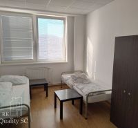 A room with two beds, a cabinet, a table, and a floor with a wooden decor.