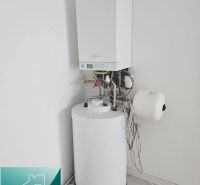 Boiler and water heater in the interior of commercial premises, with a wooden decor floor.