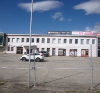 Commercial premises on Strojnícka Street in Prešov with a concrete parking lot and company signs.