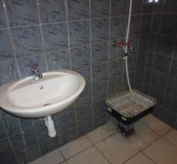 Bathroom in commercial premises with a ceramic sink and dark tiles on the walls.